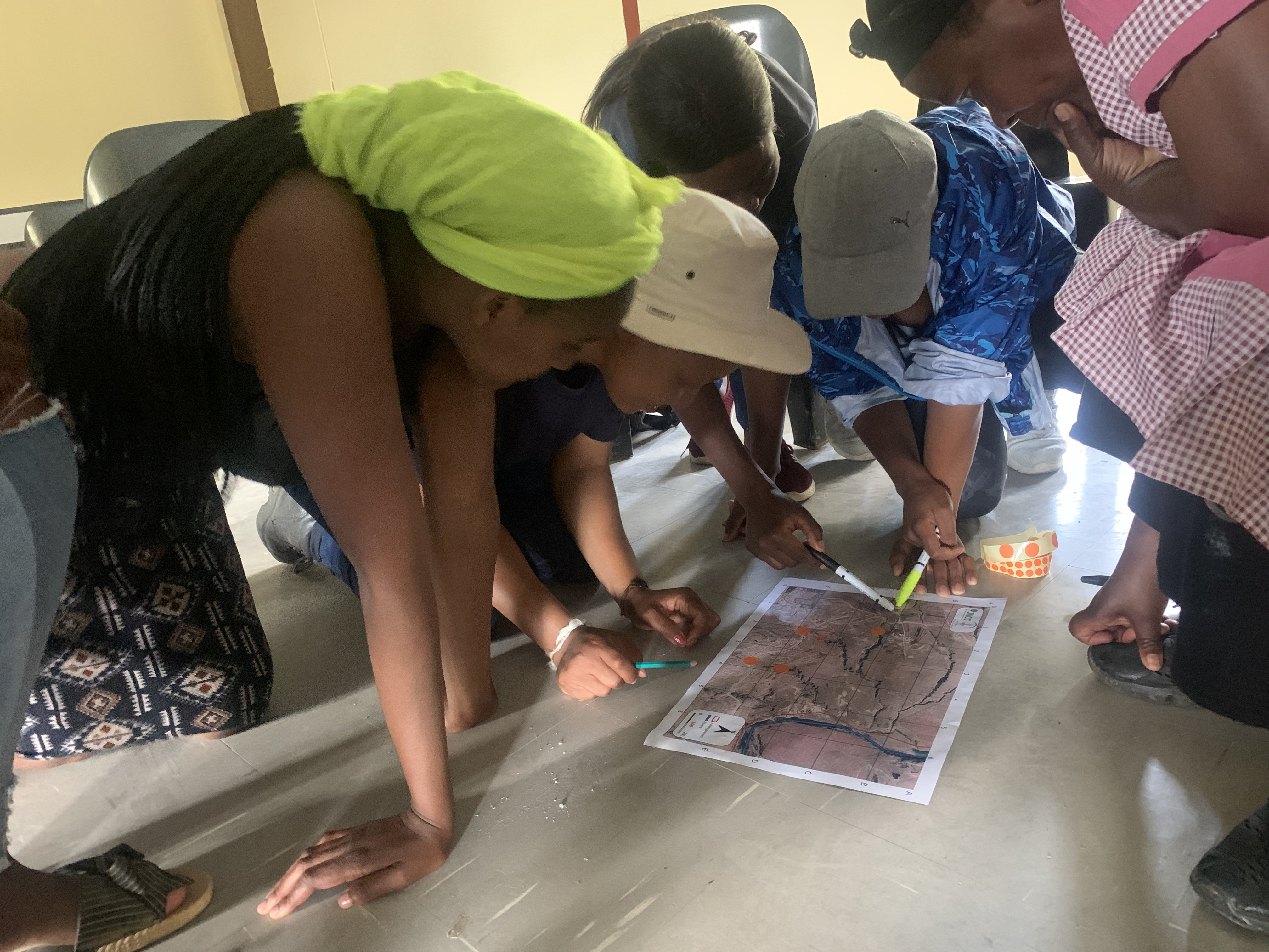 Photo of people gathered around looking and pointing at a map