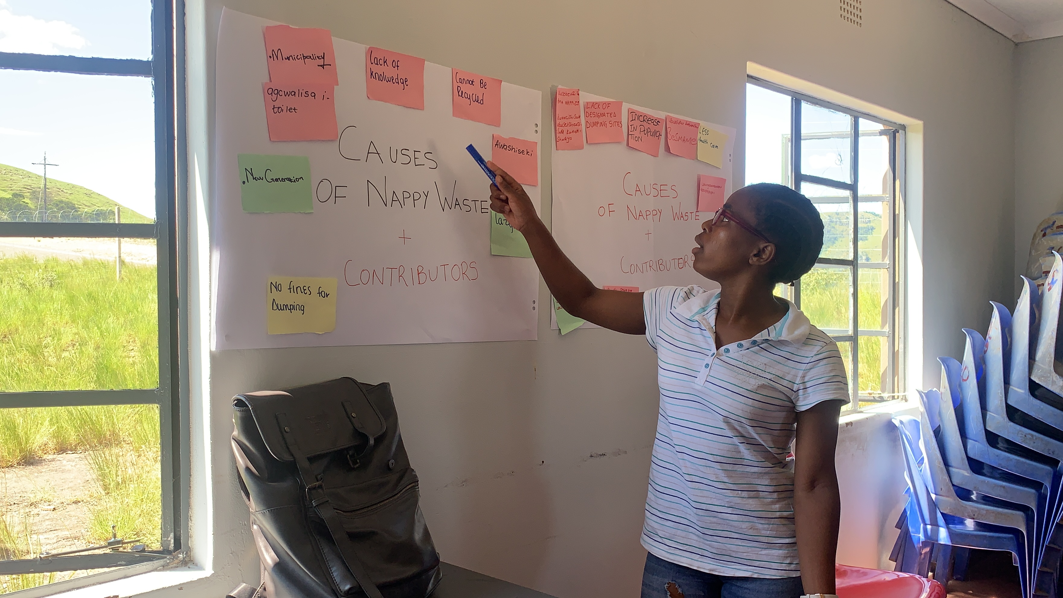Photo of a person stood pointing at a poster with post it notes stuck to it 