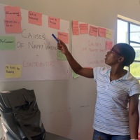 Photo of a person stood pointing at a poster with post it notes stuck to it 