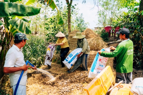 Photograph of three people emptying bags of straw whilst one person sprays with water (© GAHP)