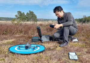 ©Kew Man kneeling on the ground with a drone on it's launch pad