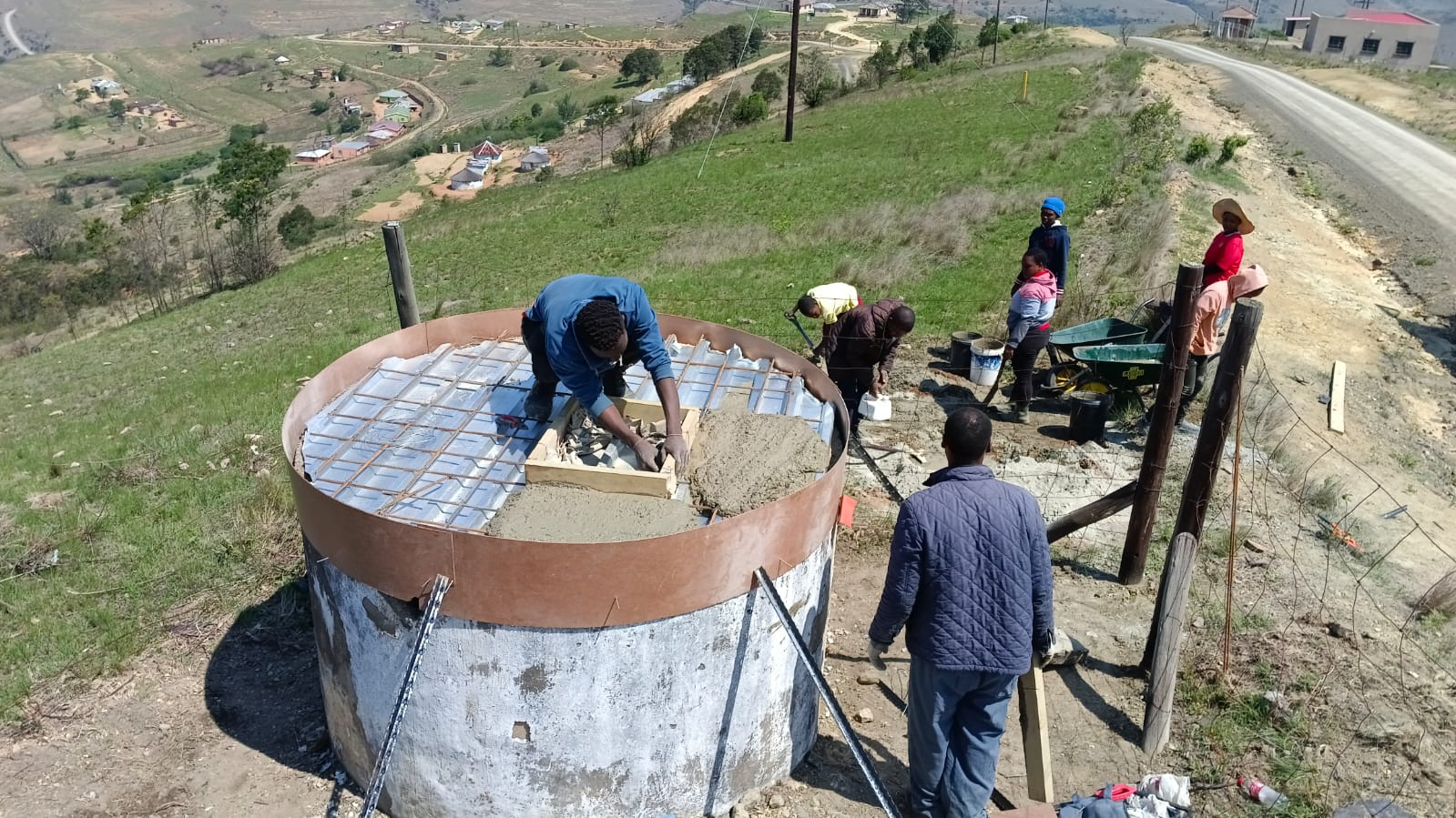 People building a concrete water tank in a rural setting