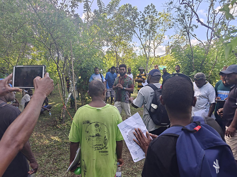 Ni-Vanuatu CCA rangers standing in woodland watching a training demonstration