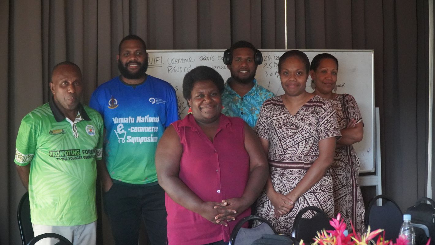 6 People standing in front of a whiteboard smiling at the camera