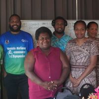 6 People standing in front of a whiteboard smiling at the camera
